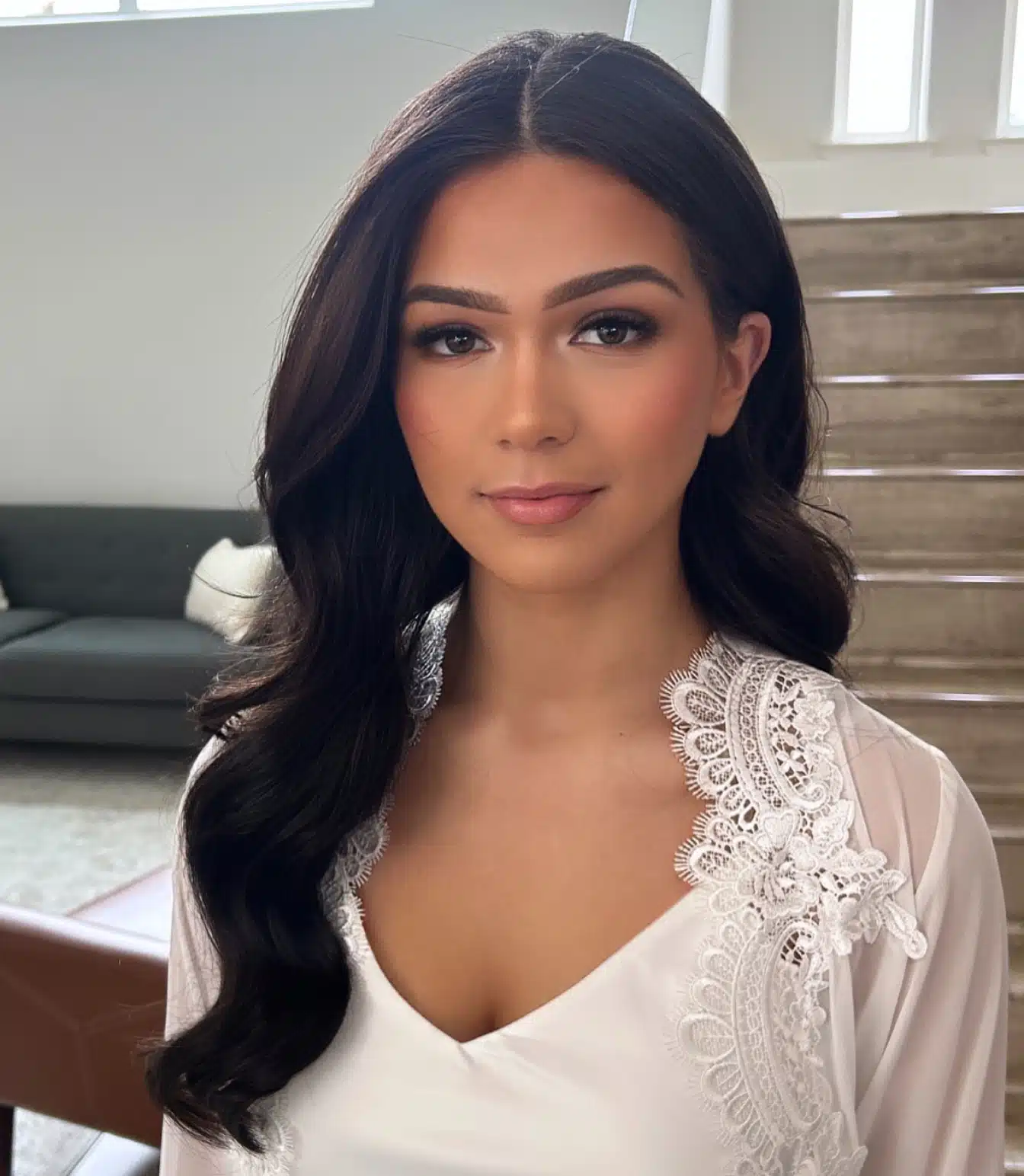 Bride in a lace robe with a center part and radiant makeup