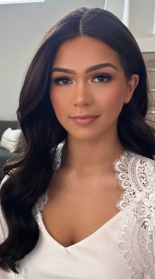 Bride in a lace robe with a center part and radiant makeup
