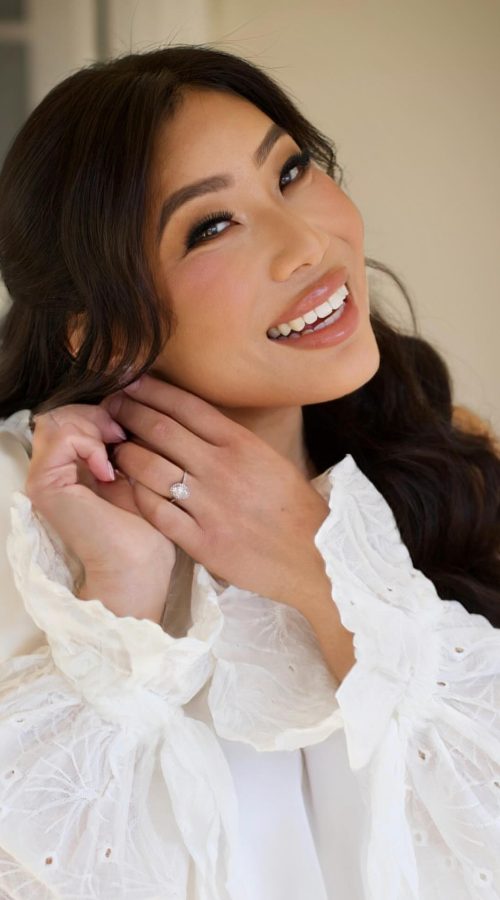 Smiling client showing her ring, with soft glam makeup and dark waves